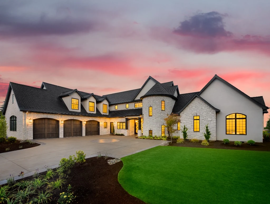 Luxury home at dusk with warm interior lighting and manicured landscaping